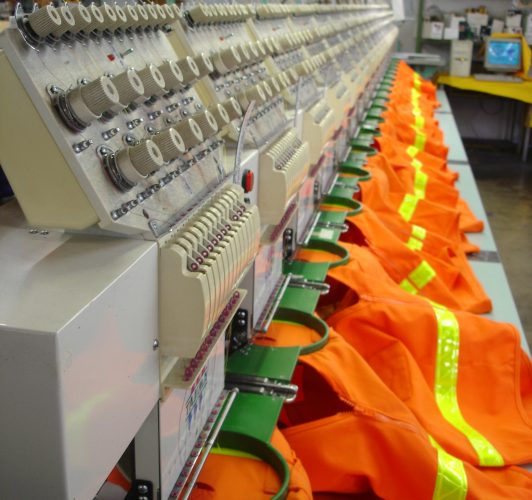 Orange safety vests being embroidery by industrial embroidery machines.